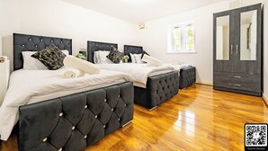 Una habitación de hotel con tres camas, un armario y un espejo grande.