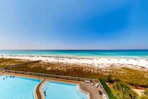 A beach view with a swimming pool and beach umbrellas.