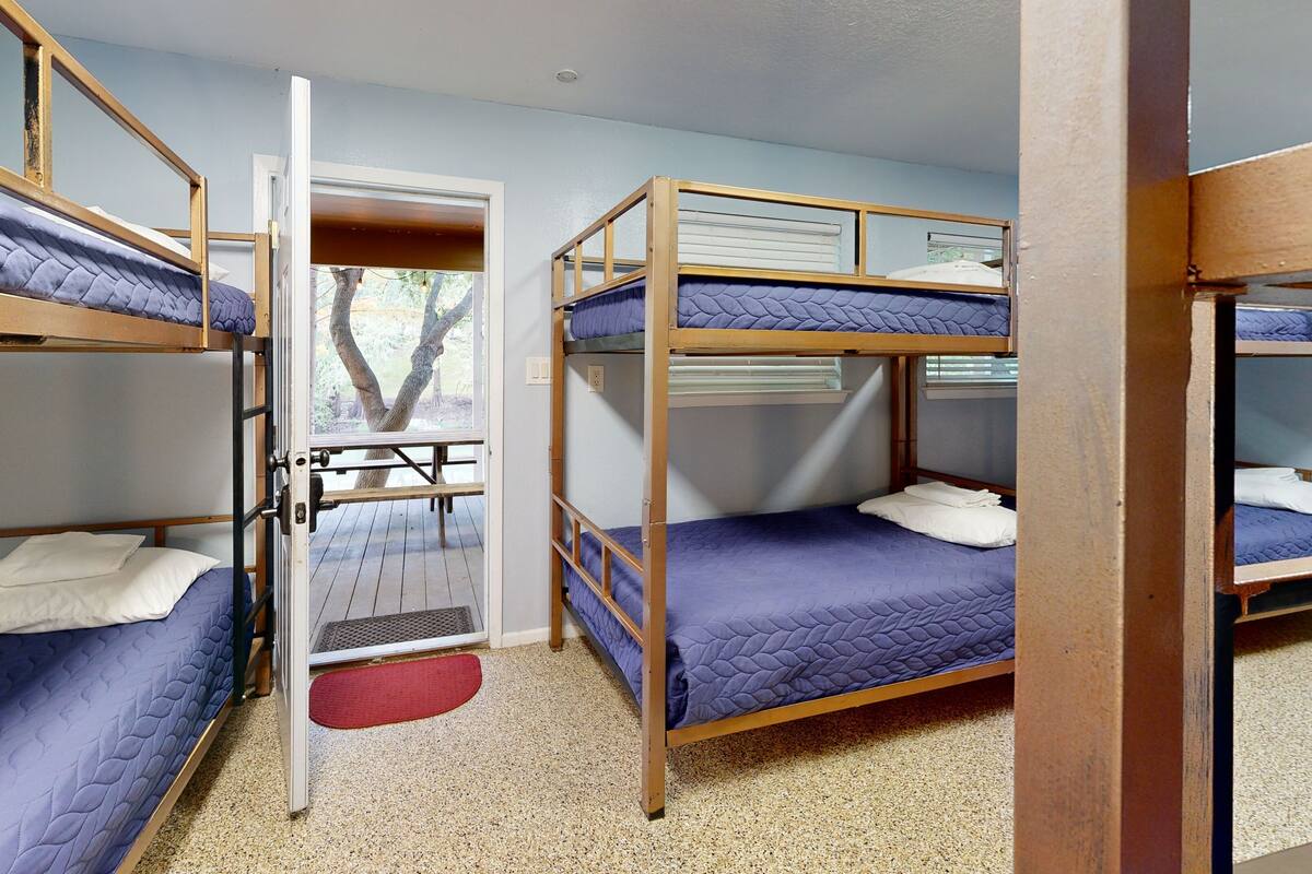 Un dormitorio con literas, una ventana y una puerta que da a un espacio exterior.
