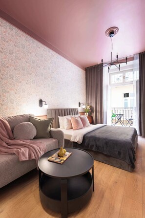A modern bedroom with a sofa, a round table, a bed, and a balcony view.