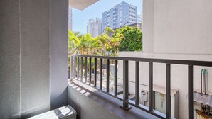 A balcony with a metal railing, a concrete wall, and a view of tall buildings and greenery. - Flat na Vila Mariana c Varanda pr x ao Metr (São Paulo)