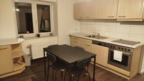 A compact kitchen with a dining table, chairs, a sink, and a stove. - AriProp Chemnitz Central Stay – 3 Guests (Chemnitz)