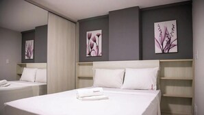 Een hotelkamer met twee bedden, wit beddengoed en kunst aan de muren.
