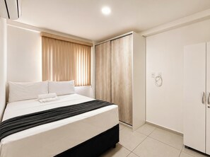 Habitación de hotel con cama, armario y zona de ducha.