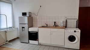 Une cuisine compacte équipée d’un réfrigérateur, d’un four à micro-ondes, d’un four, d’un lave-vaisselle et d’une machine à laver.