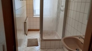 Une salle de bain avec une douche, un lavabo et un radiateur.