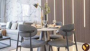 A modern dining area with a marble wall, a wooden slat partition, and a round table set for two. - Vogue | Downtown near Dubai Mall | Burj Khalifa (Dubai)