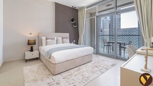 A modern bedroom with a large bed, a nightstand, a lamp, a view of the city through large windows, and a balcony with outdoor furniture. - Vogue | Downtown near Dubai Mall | Burj Khalifa (Dubai)