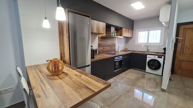 A modern kitchen with a wooden table, stainless steel appliances, and a washing machine.
