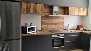 A modern kitchen with wooden cabinets, a built-in microwave, a stove, and a small plant on the countertop.