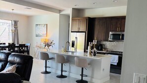 A modern kitchen with dark wooden cabinets, stainless steel appliances, and a central island with bar stools. - New- Villa white Peacock Exclusive Villa with all amenities, top location (Cape Coral)