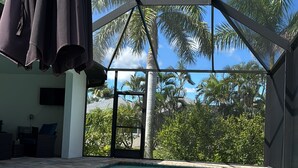 A swimming pool with a view of palm trees and a covered area with seating. - New- Villa white Peacock Exclusive Villa with all amenities, top location (Cape Coral)