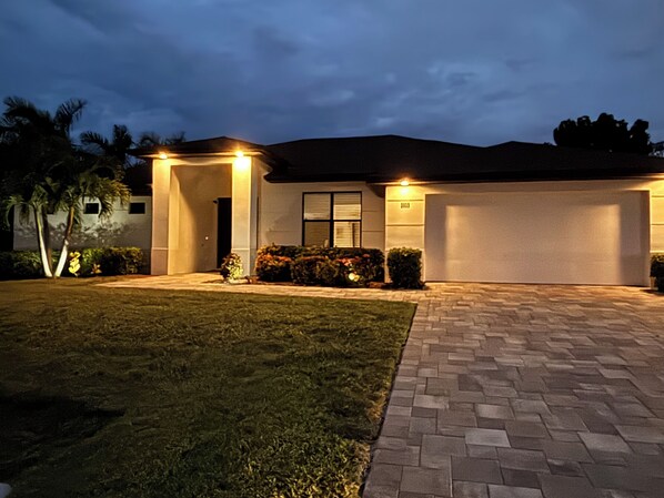 A residential house with a paved driveway, a well-maintained lawn, and a garage. - New- Villa white Peacock Exclusive Villa with all amenities, top location (Cape Coral)