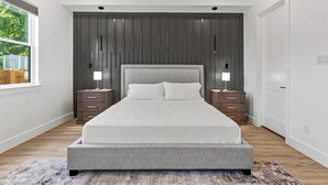 Un dormitorio moderno con una cama grande, dos mesitas de noche y vistas a zonas verdes.