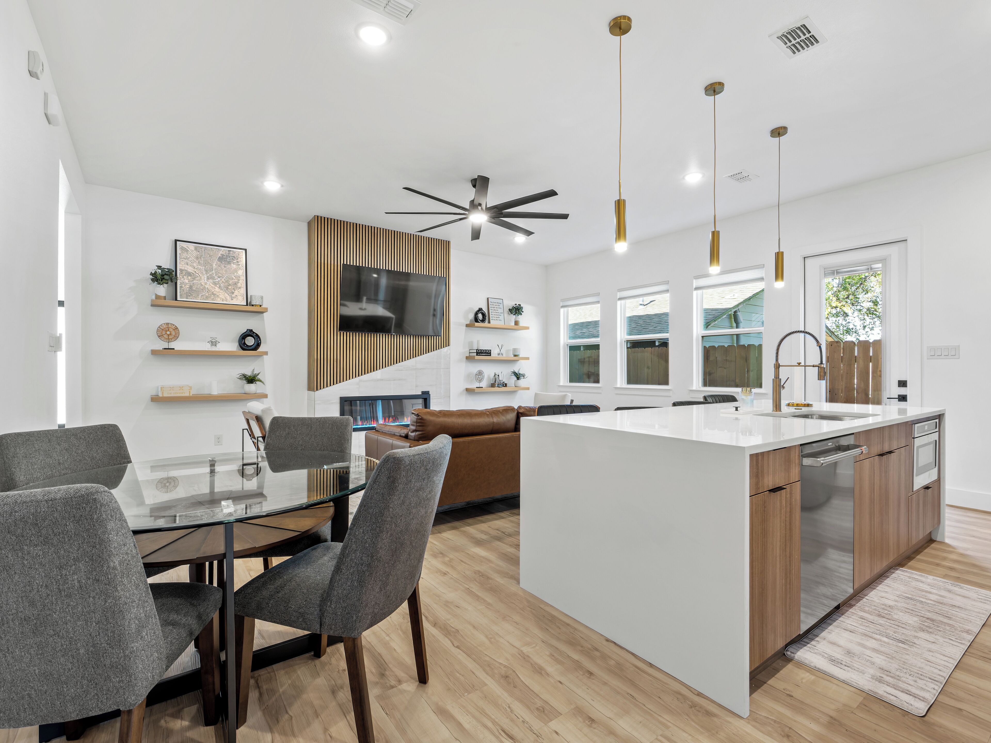 Une cuisine moderne dotée d’un îlot central, de meubles en bois et d’un téléviseur encastré.