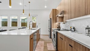 Una cocina moderna con una isla central, armarios de madera y electrodomésticos de acero inoxidable.