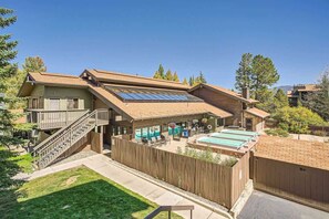 A two-story house with a wooden deck, a swimming pool, and a fenced backyard.