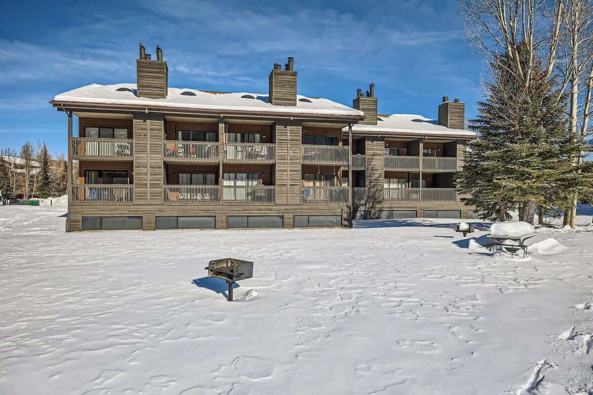 A multi-story building with balconies, a snow-covered ground, and a clear sky.