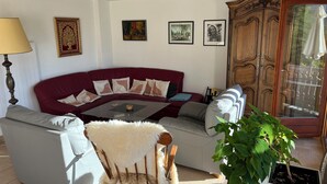 Ein Wohnzimmer mit einem roten Sofa, einem weißen Sessel, einem Glastisch und einem Holzschrank.