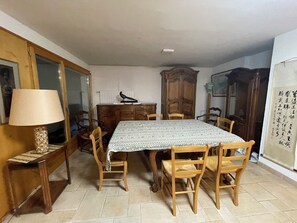 Een eetgedeelte met een tafel, stoelen, een lamp en een kast.