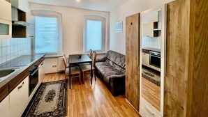 A compact kitchen with a dining area, a sofa, and a wooden wardrobe. - Comfort apartment for 4 guests in Chemnitz K1R (Chemnitz)