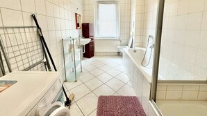 A bathroom with a shower, toilet, sink, and a window. - Comfort apartment for 4 guests in Chemnitz K1R (Chemnitz)