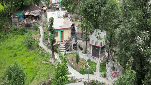 A rural house with a small garden, a staircase leading to a porch, and a nearby water tank. - Peace Forest Retreat (Chamoli)