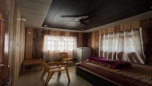 A cozy room with a bed, a chair, a small table, and a ceiling fan. - Peace Forest Retreat (Chamoli)