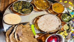 A traditional Indian meal with various dishes on a metal tray. - Peace Forest Retreat (Chamoli)