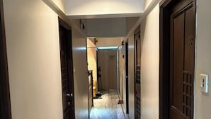 A hotel hallway with marble flooring, dark wooden doors, and a ceiling light. - Pravasi Residency (Mumbai)