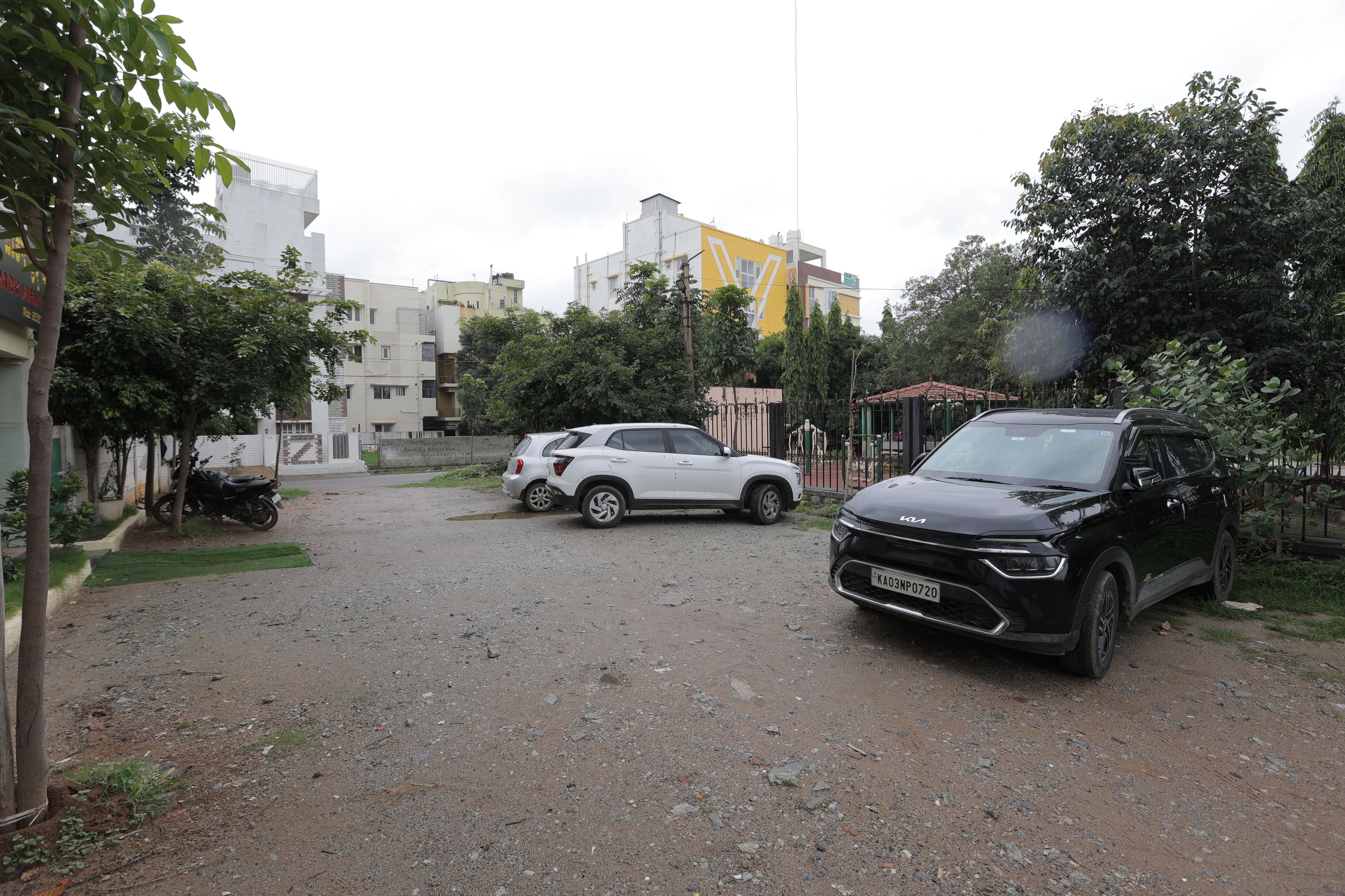 A parking area with a black SUV, a white SUV, and a motorcycle.