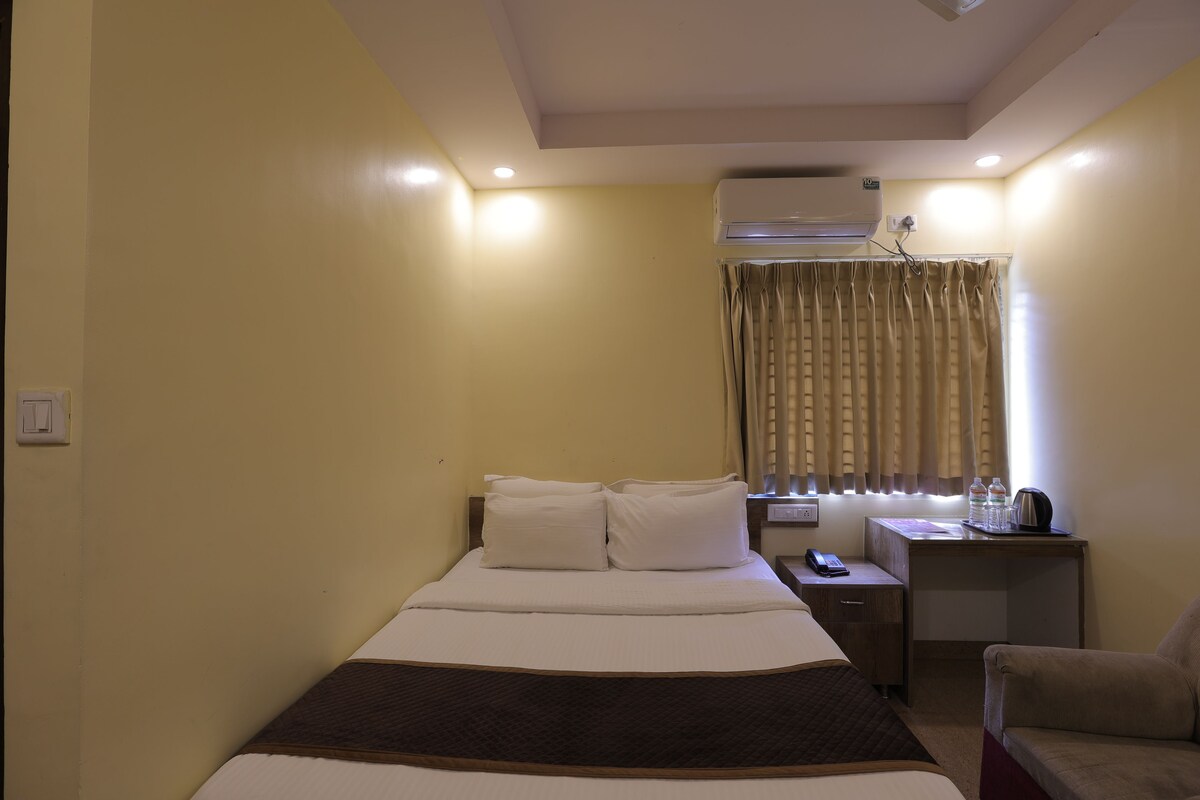 Ein Hotelzimmer mit Bett, Nachttisch, Sessel und Klimaanlage.