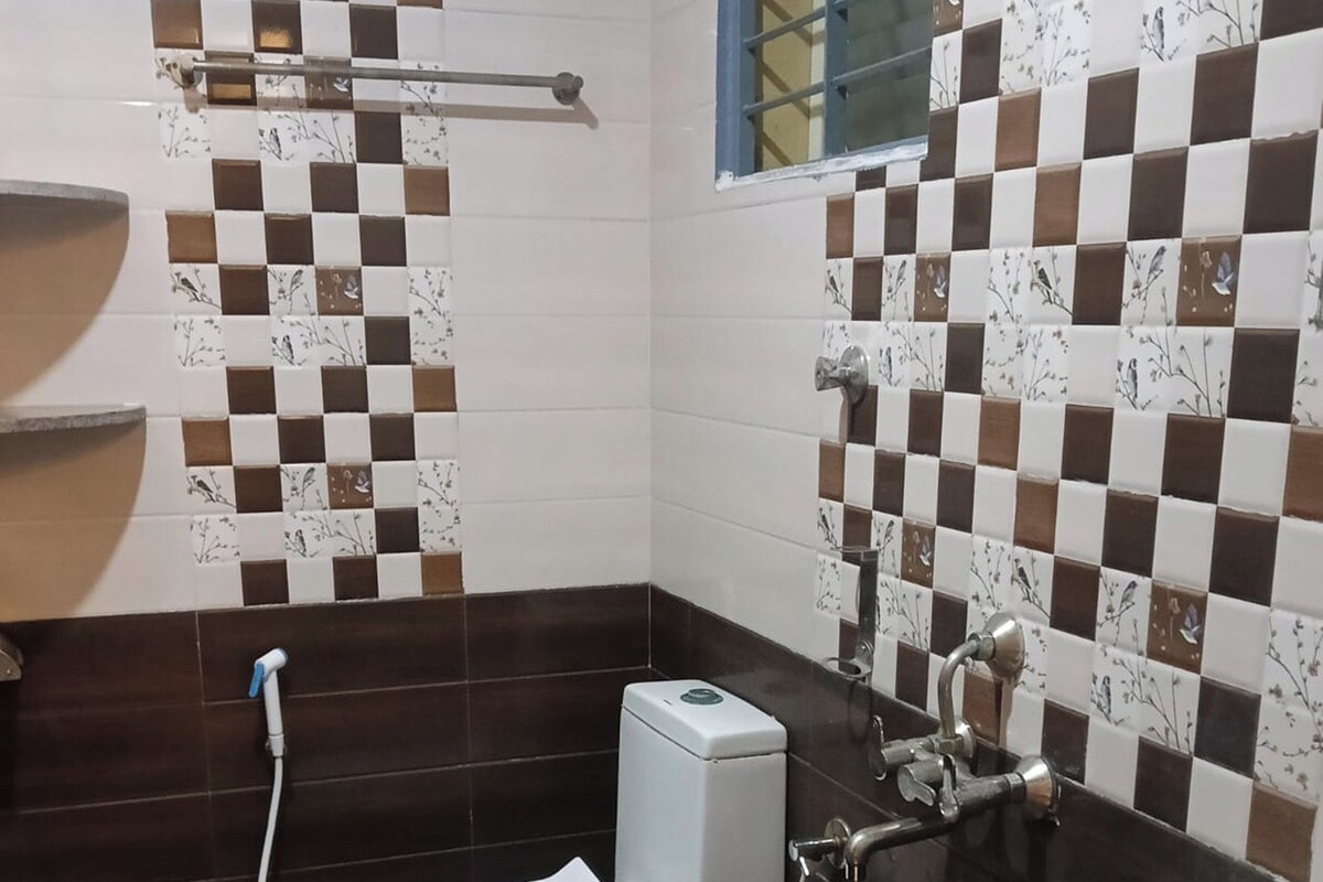 Ein Badezimmer mit Toilette, Bidet und Waschbecken, mit Schachbrettmuster-Wandfliesen und dunklen Bodenfliesen.