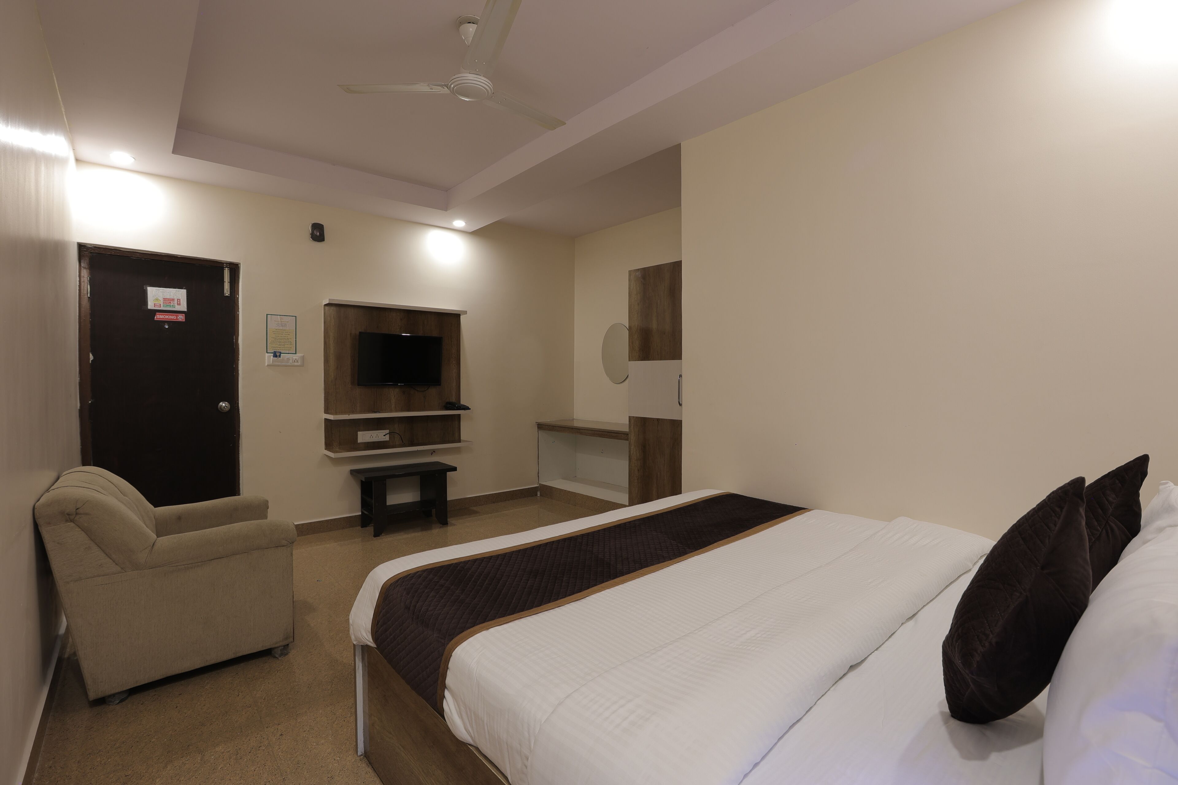A hotel room with a bed, a chair, a TV, and a desk.
