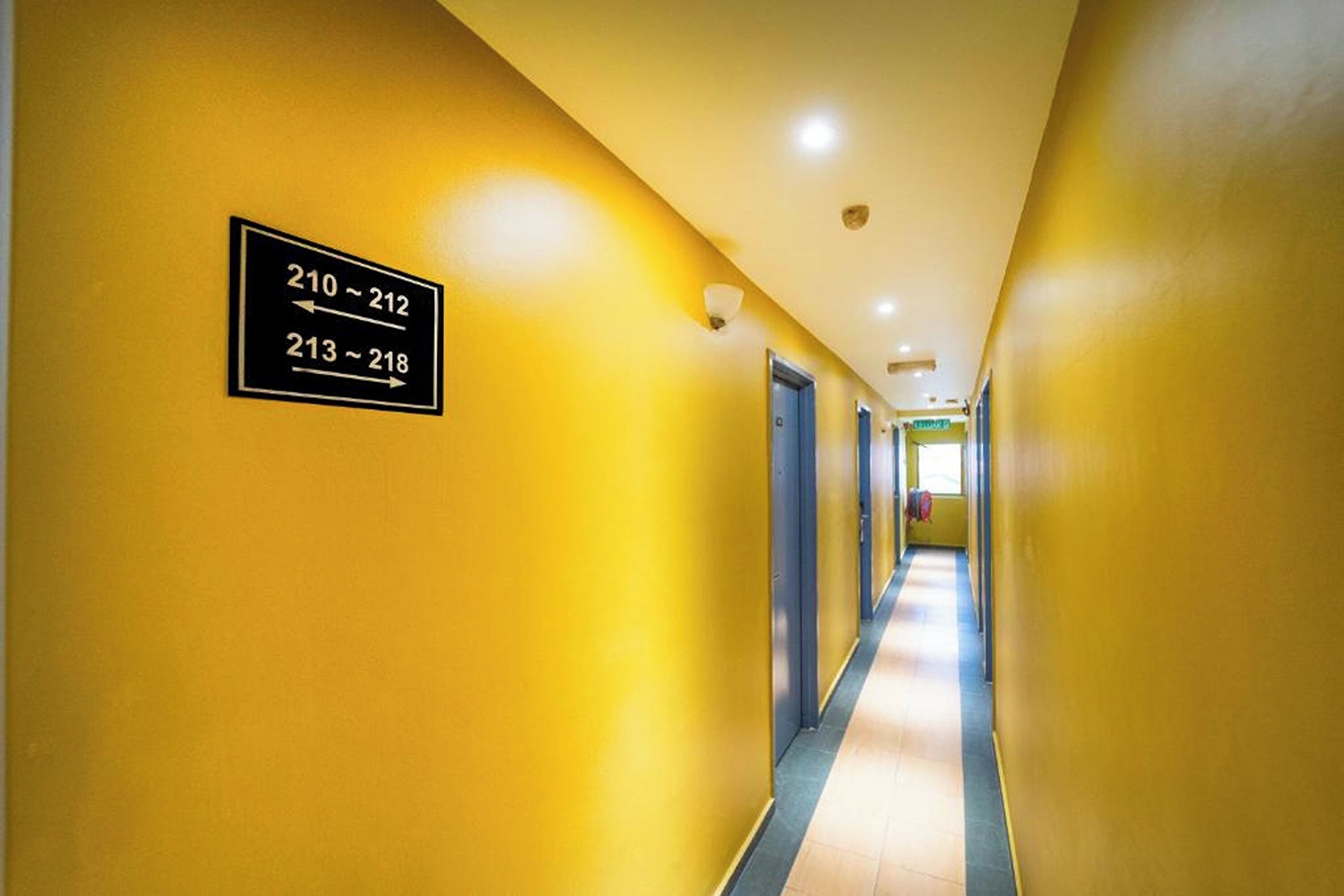 A hotel hallway with directional signs for room numbers 210-212 and 213-218.