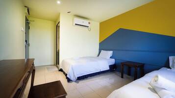 A hotel room with two beds, a wooden dresser, and an air conditioning unit on the wall.