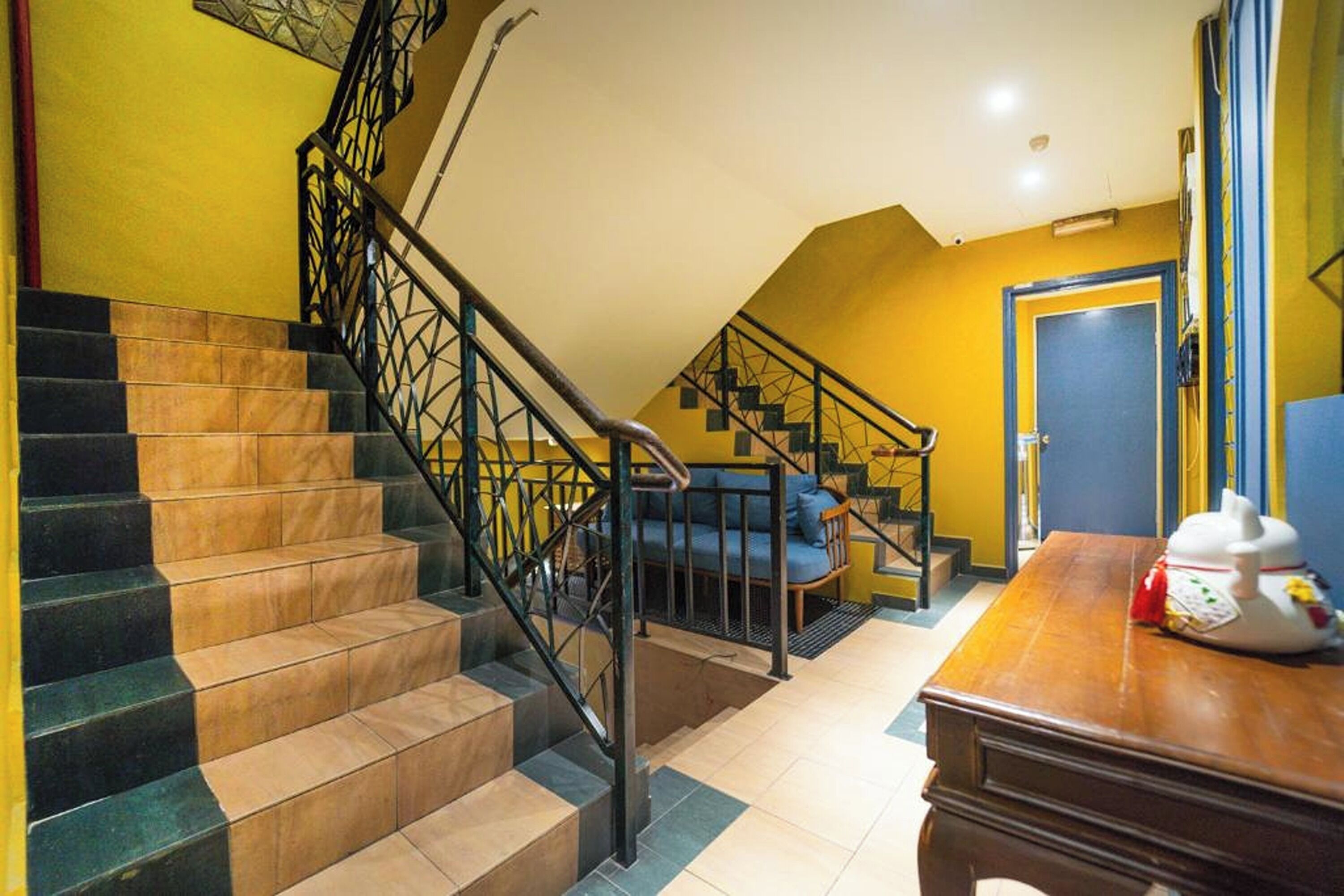 A staircase with alternating black and beige steps, a blue sofa, and a wooden table with a teapot.