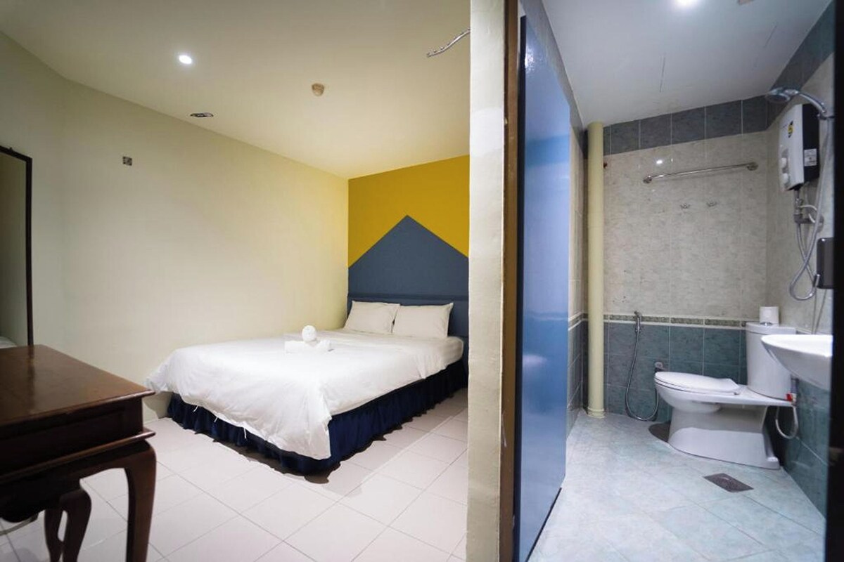 Ein Hotelzimmer mit Bett, Schreibtisch und einem Badezimmer inklusive Toilette und Waschbecken.