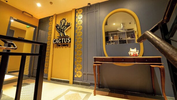A hotel lobby with a 'Cactus The Colony' sign, a mirror, and a small table with a figurine. - The Colony By Cactus Hotel Johor Jaya (Johor Bahru)