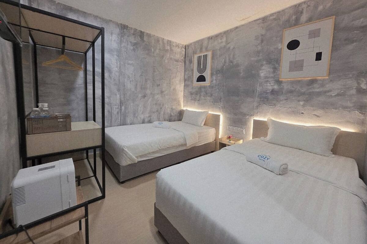 Una camera d'albergo con due letti, uno specchio, un comodino e un'opera d'arte appesa al muro.