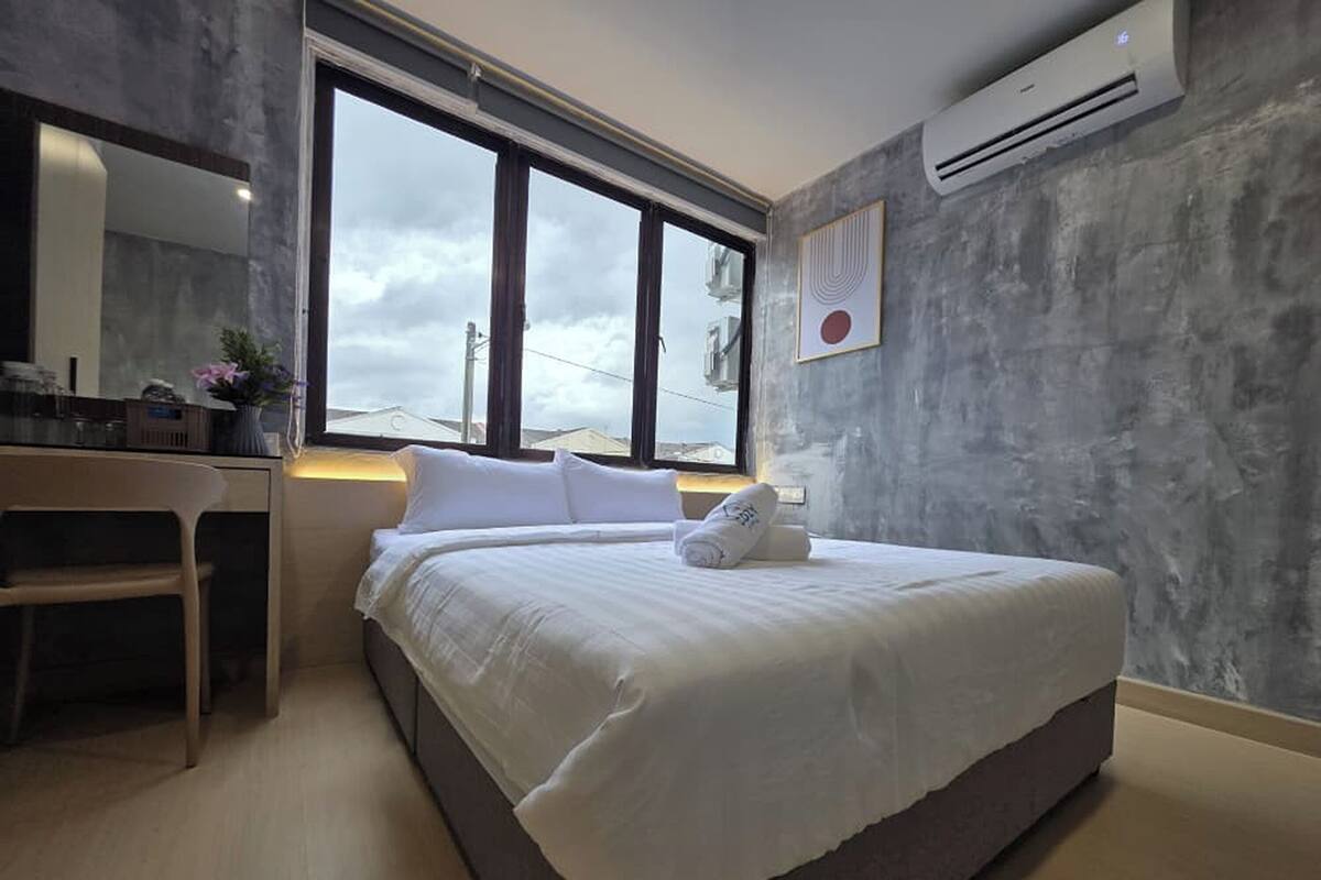 Camera d'albergo moderna con un letto grande, una scrivania e una finestra che offre vista sul cielo.