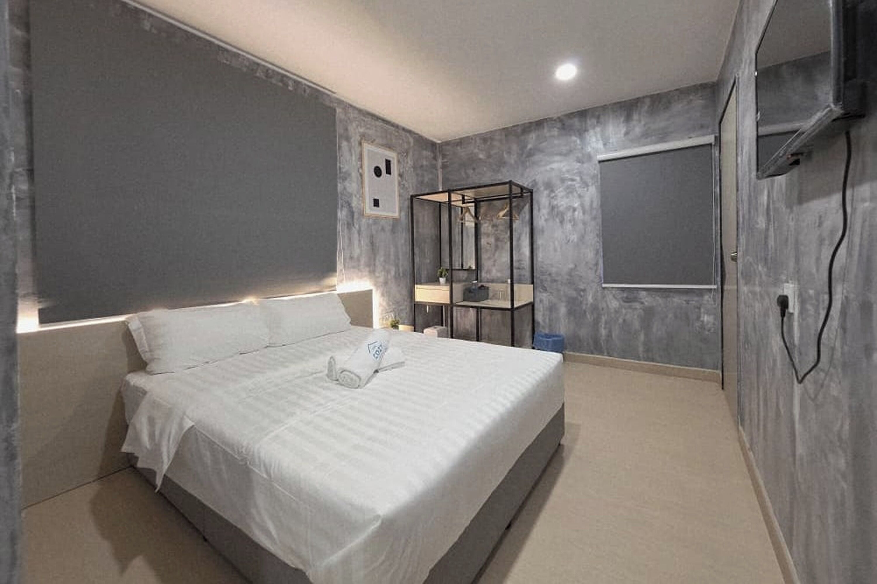 A modern bedroom with a large bed, a bedside table with a lamp, and a wardrobe with a mirror.