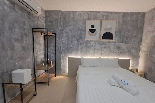 A modern hotel room with a large bed, a bedside table, a wardrobe, and a wall-mounted air conditioner. - The Cozy Hotel (Sungai Petani)