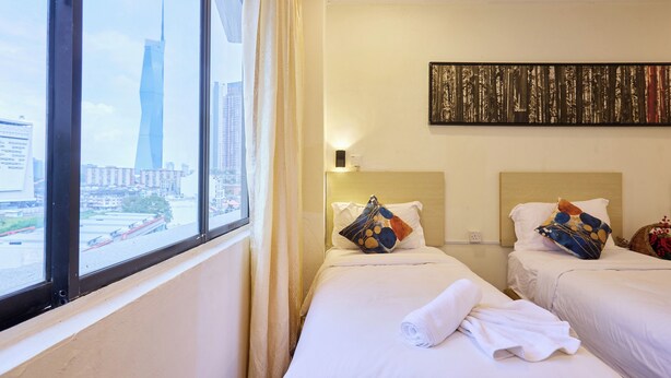 Een hotelkamer met twee bedden, een groot raam en uitzicht op de stad.