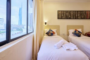 Een hotelkamer met twee bedden, een groot raam en uitzicht op de stad.