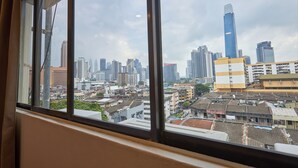 Stadsgezicht door een raam met uitzicht op hoge gebouwen en een mix van oudere en moderne architectuur.