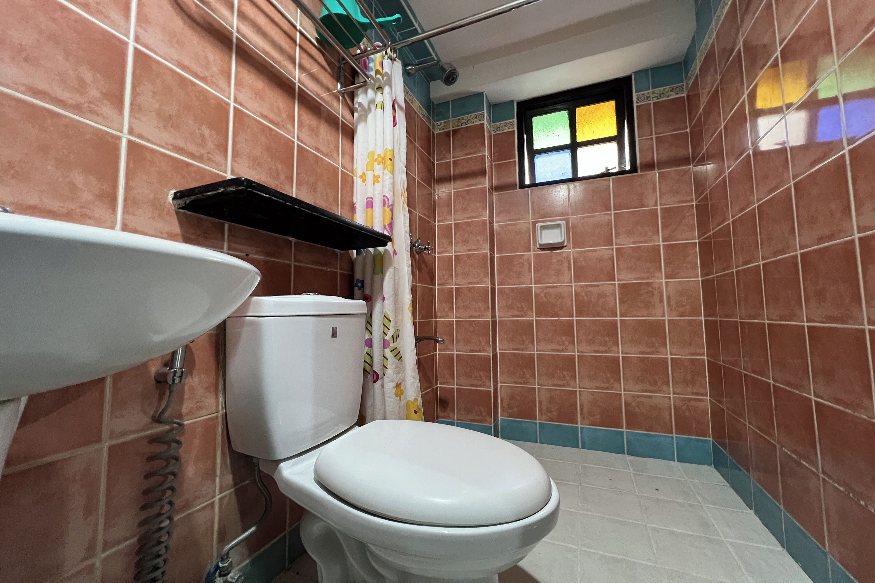 Un baño con inodoro, lavamanos y cortina de ducha.