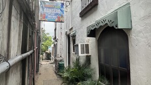 A narrow alleyway with buildings on either side, a sign for a restaurant, and potted plants along the path. - Bangera Inn (Puerto Galera)