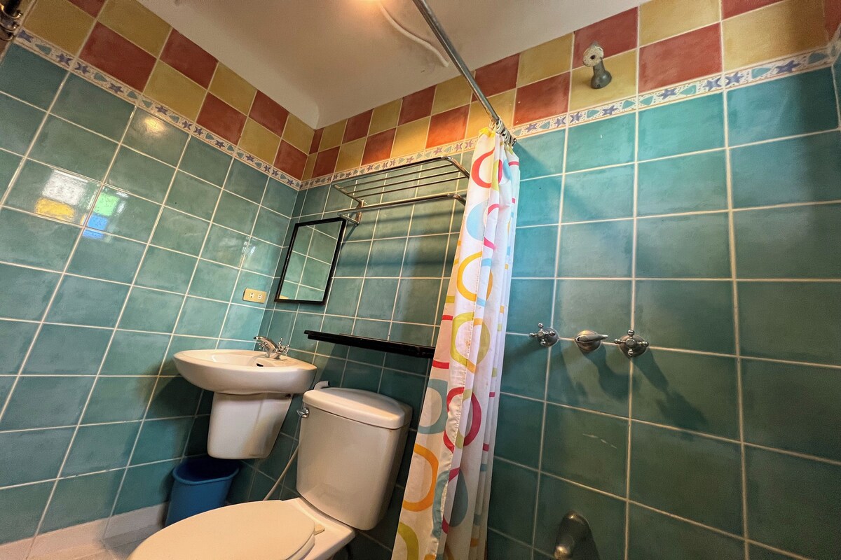 Un baño con inodoro, lavamanos y cortina de ducha.