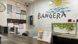 A reception desk with a calendar, a fish tank, and a wall with the word 'BANGERA'. - Bangera Inn (Puerto Galera)